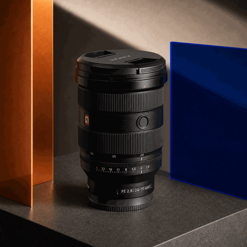 Sony FE 24-70mm F2.8 GM II lens standing on a cobalt, orange and charcoal FRAMEHAUS studio set